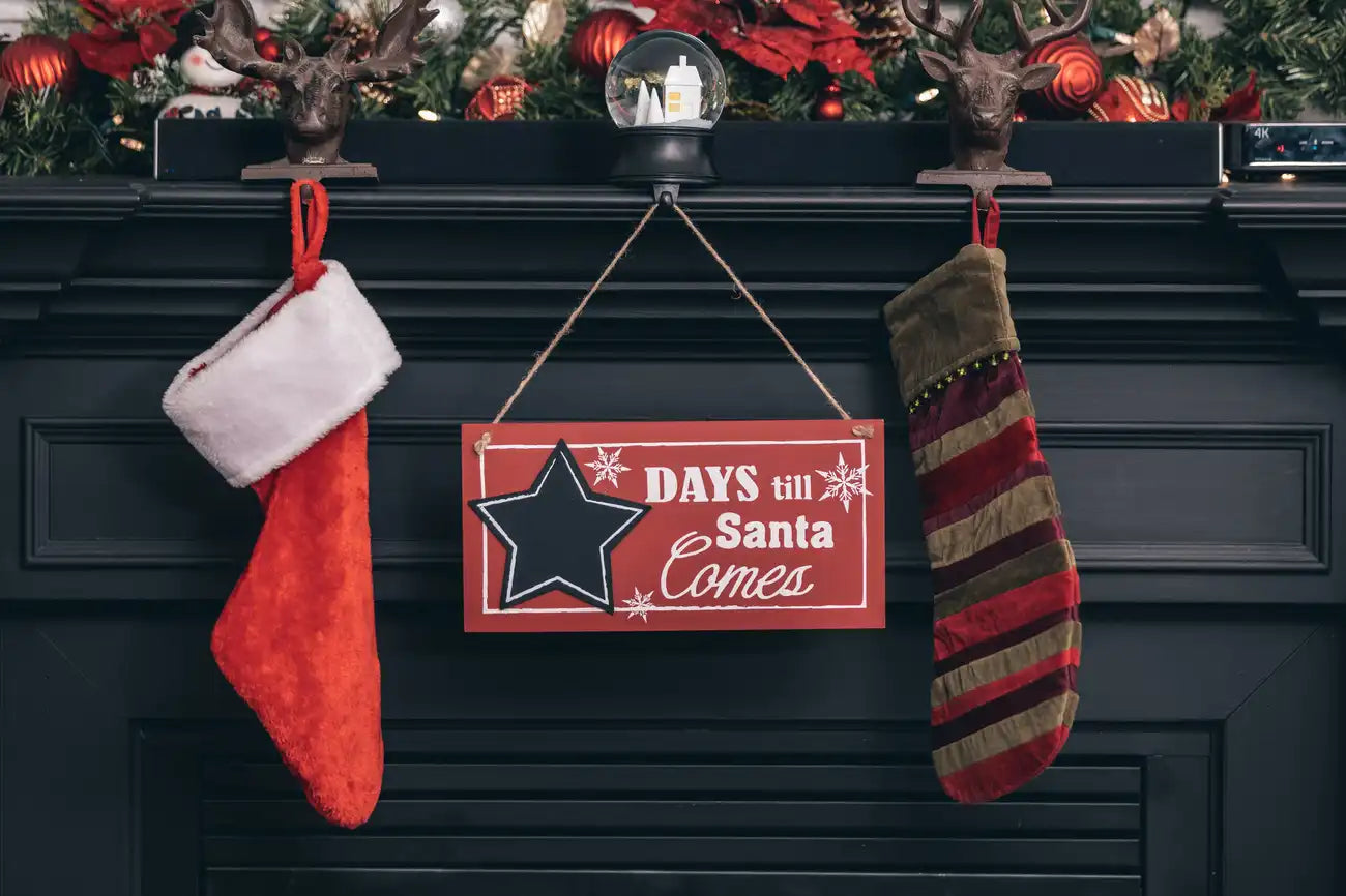 Decorative Christmas mantel with stockings and a sign over a fireplace at canagem.