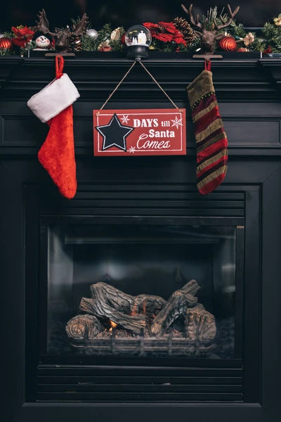 Decorative Christmas mantel with stockings and a sign over a fireplace at canagem.